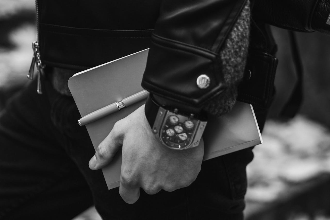 The Art of Drawing Readers In: Your attractive post title goes here A person in leather jacket holding notebook and pen, highlighting style and productivity.